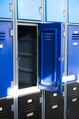 Fototapeta premium Open blue upper locker is revealing empty shelves on hall wall, with sunlight showing scuff marks