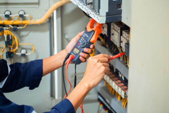 Professional Electrician Testing Electrical Control Panel with Digital Clamp Meter for Preventive Maintenance and Troubleshooting