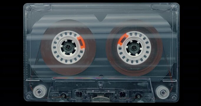 Vintage Audio Cassette with Spinning Reels. Transparent tape cassette with rotating reels on black background, evoking analog recording and retro technology.