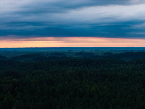 Aerial view of Kemeri National Park featuring the Kemeru Kalni dune ridge covered in dense forest under a dramatic sunset sky in Jurmala, Latvia.