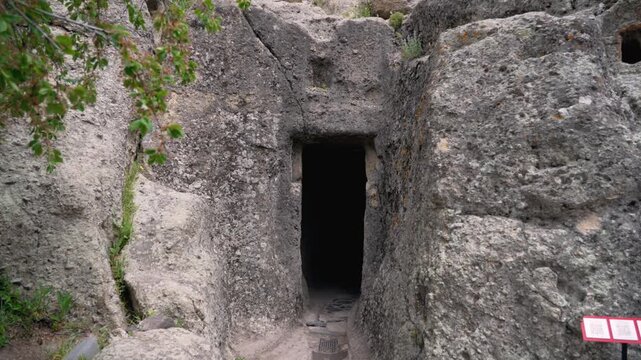 Cave entrance in a rocky area near Khor Virap Monastery. Exploring a cave entrance in a rocky area with ancient carvings at a historical site.A cave entrance is visible in a rocky area surrounded by t