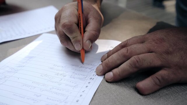 A man puts his signature on a piece of paper to register his vote. Close-up shooting