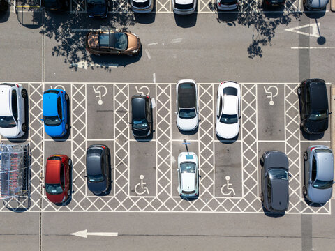 Aerial view of a parking lot with various cars parked in designated spaces including marked disabled parking spots in London, England, United Kingdom.