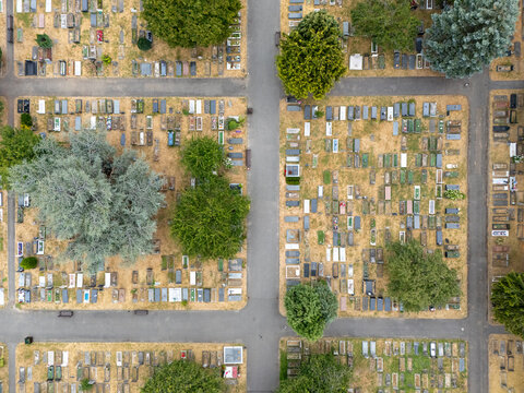 Aerial view of Gunnersbury Cemetery featuring organized rows of graves, intersecting pathways, and mature green trees in London, England, United Kingdom.