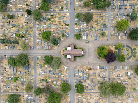 Aerial view of Gunnersbury Cemetery featuring a central chapel surrounded by rows of gravestones, pathways, and mature trees in London, England, United Kingdom.