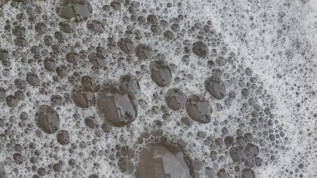Close-up of foam bubbles slowly moving across a liquid surface, creating an abstract organic texture and relaxing macro background.