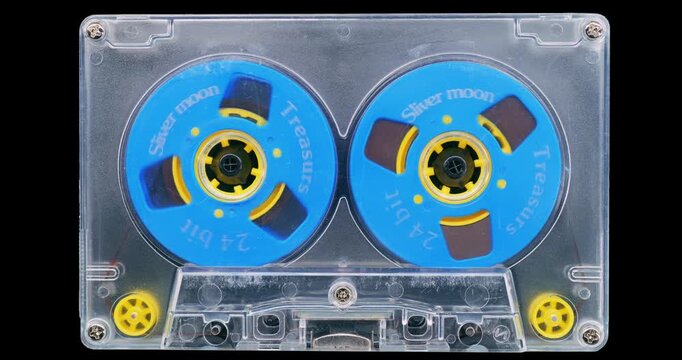 Transparent Audio Cassette with Blue Reels. Front view of a vintage cassette with bright blue reels spinning on a black background.