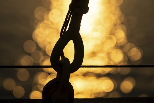 Part of the rigging of a sailing ship, anchoring, steel cable, back light, sunset, silhouette, bokeh effect, Sicily, Italy