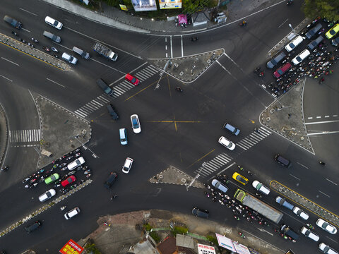 Aerial view of the busy Condong Catur intersection with heavy traffic of cars and motorcycles navigating the asphalt roads in Depok, Yogyakarta, Indonesia.
