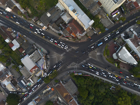 Aerial view of the Condong Catur intersection with heavy traffic flow, urban buildings, and surrounding greenery in Depok, Special Region of Yogyakarta, Indonesia.