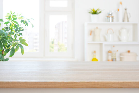 Empty kitchen table top with copy space on blurred interior and green houseplant background