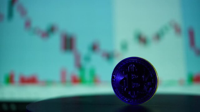 Cryptocurrency coin sits upright in the foreground while colorful stock market candlestick charts glow softly in the blurred background, representing modern digital financial trading and market.