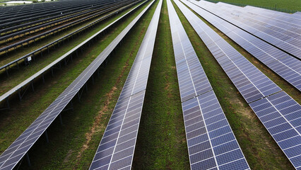 Solar farm generating clean electricity with long rows of photovoltaic panels on green grass for sustainable energy © Volodymyr_sh