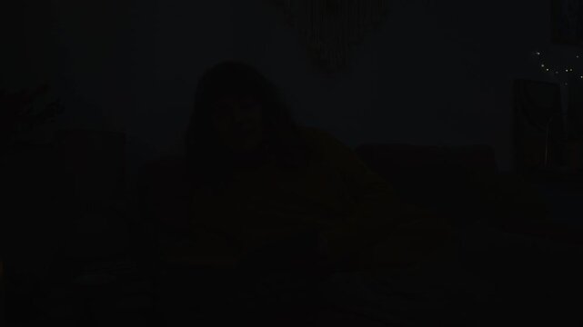 Caucasian young woman reading book in bed when lights suddenly flicker and go out. Video is perfect for home safety campaigns, energy crisis promos, or thriller movie trailers