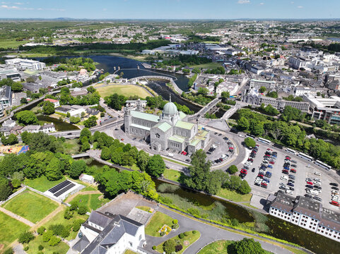 Aerial view of Galway Cathedral surrounded by green spaces, the River Corrib, and urban infrastructure in Galway, County Galway, Ireland.