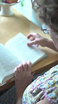Back view from behind of a senior woman reading a book closeup