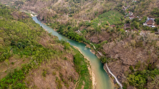 Aerial view of Sungai Oya winding through lush green hills and terraced fields, Kecamatan Imogiri, Daerah Istimewa Yogya, Indonesia.
