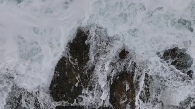Drohnenaufnahme eines Felsen mit Brandung in einem Meer nach einem Sturm. Italienische Insel. Das Wasser sch&auml;umt an einem Felsen. Brandung. Laute Wasser Ger&auml;usch. Drohnenaufnahme von oben