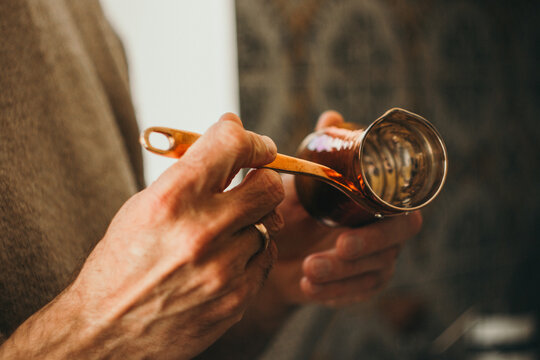 Close-up of hands presenting a traditional copper coffee pot with elegant craftsmanship and timeless design.