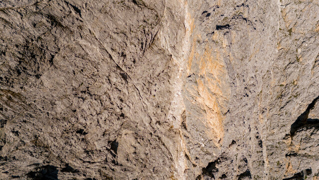 Aerial view of the rugged limestone rock face of the Dolomites with deep crevices and geological textures in San Martino di Castrozza, Trentino-Alto Adige, Italy.