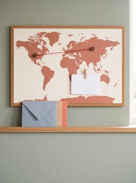 World map with red string connecting two pins and letters