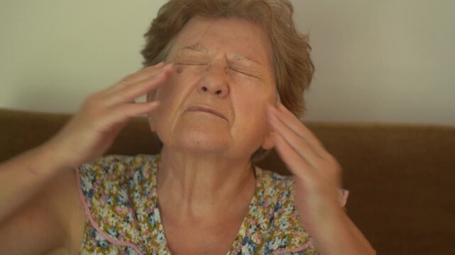 A senior woman with a headache and expression of pain