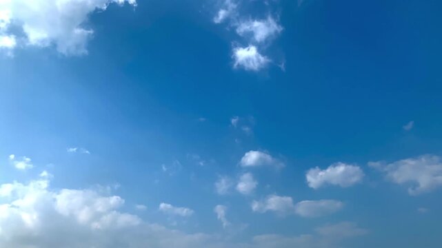 Bright cumulus clouds beneath a vivid blue sky, refreshing atmospheric texture background with smooth cloud movement, perfect for travel, environment, landscape, and commercial footage.