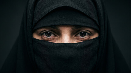 Naklejka premium Close-up portrait of a Muslim woman wearing a traditional black niqab, with only her expressive eyes visible, surrounded by others.