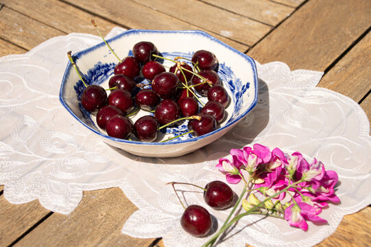 Fresh Ripe Cherries in Sunlight on a Rustic Cottage Garden Table