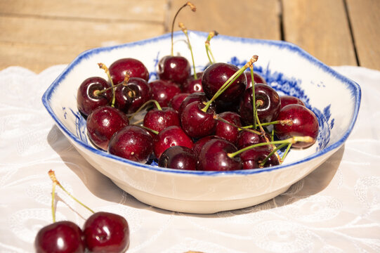 Fresh Ripe Cherries in Sunlight on a Rustic Cottage Garden Table