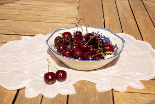 Fresh Ripe Cherries in Sunlight on a Rustic Cottage Garden Table