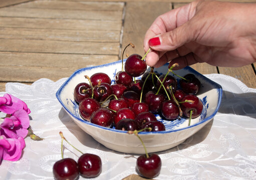 Fresh Ripe Cherries in Sunlight on a Rustic Cottage Garden Table