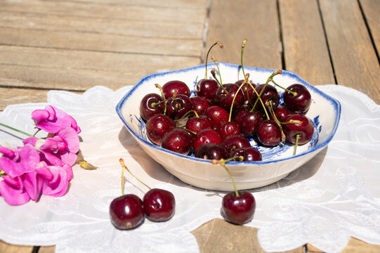 Fresh Ripe Cherries in Sunlight on a Rustic Cottage Garden Table