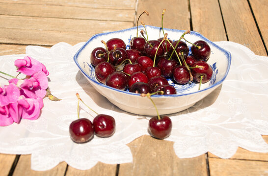 Fresh Ripe Cherries in Sunlight on a Rustic Cottage Garden Table