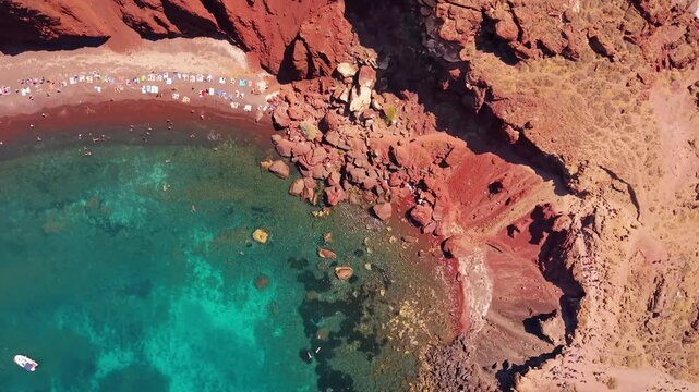 Top-down aerial shot over red volcanic coast and clear turquoise water at Red Beach Santorini