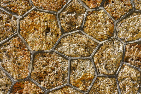 Warme Natursteinmauer mit unregelm&auml;&szlig;igen dunklen Fugen als Textur
