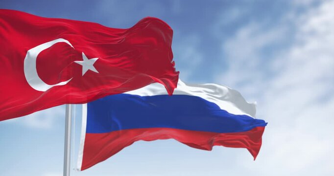 Turkish and Russian national flags waving in the wind on a clear day