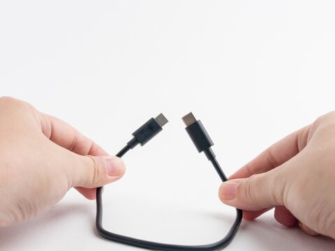 Person hand holding black USB type C charging and data cable isolated on white background