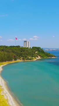 Vertical video. Eceabat, Turkey. Canakkale Martyrs Memorial, four massive stone-clad pillars supporting a concrete slab, aerial view over the Dardanelles Strait on a clear sunny day. Aerial View. Ric