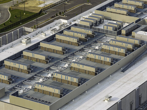 Aerial view of data center roof featuring rows of industrial cooling units and HVAC systems on a flat white surface in Aurora, Illinois, United States.