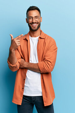 A portrait of a smiling man with glasses, a beard, and a multicolored shirt over a white shirt, set against a solid vivid background.