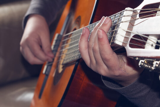Close-up of hand playing chords on an acoustic guitar