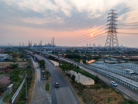Aerial view of Jalan Tambak Mulyo at sunset, featuring a highway, power lines, industrial infrastructure, and coastal surroundings in Kecamatan Semarang Utara, Jawa Tengah, Indonesia.