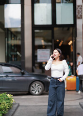 Fototapeta premium Young woman having a conversation on a mobile phone, communicating with technology in an urban environment while standing on a city street