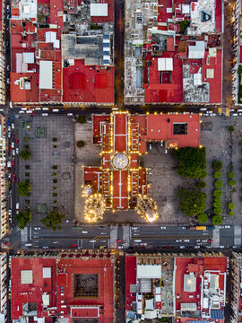 Aerial view of the illuminated Morelia Cathedral situated in the historic Plaza de Armas surrounded by red rooftops and urban streets in Morelia, Michoacan, Mexico.