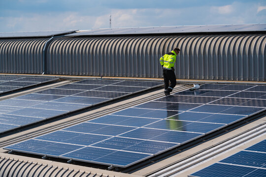 Solar electricity power technology for sustainable energy, solar panel worker roof safety energy renewable maintenance electricity industrial uniform technician walking rooftop solar array during
