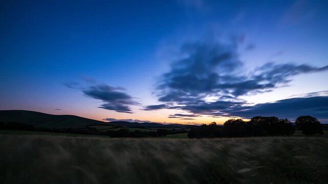 Sunset over rolling hills and grassy fields with clouds