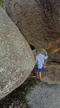 Woman and child enter gap between large stones