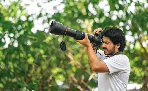 Wildlife photographer with telephoto camera in natural environment. Nature photographer using professional camera with telephoto lens