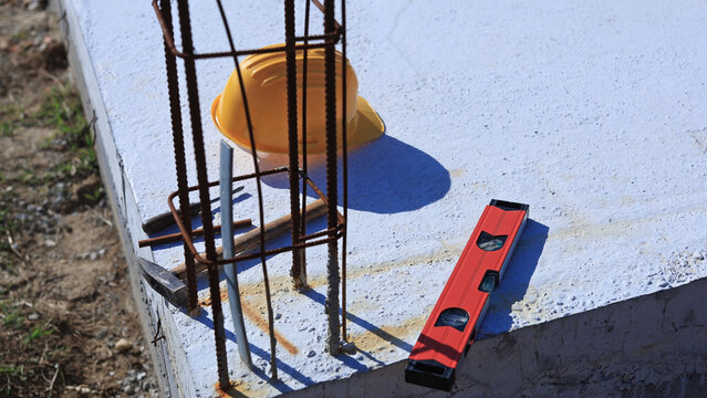 Construction tools and helmet on a cement foundation with iron rebar.